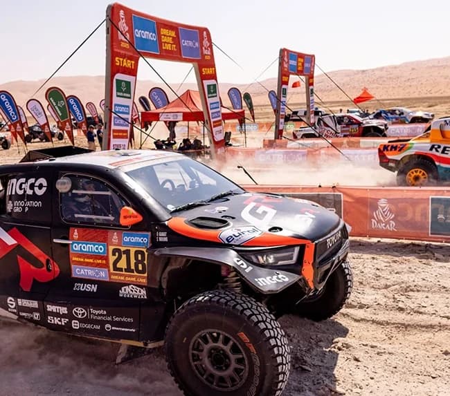 Dakar Rally — Rally vehicle beside a start arch in the desert